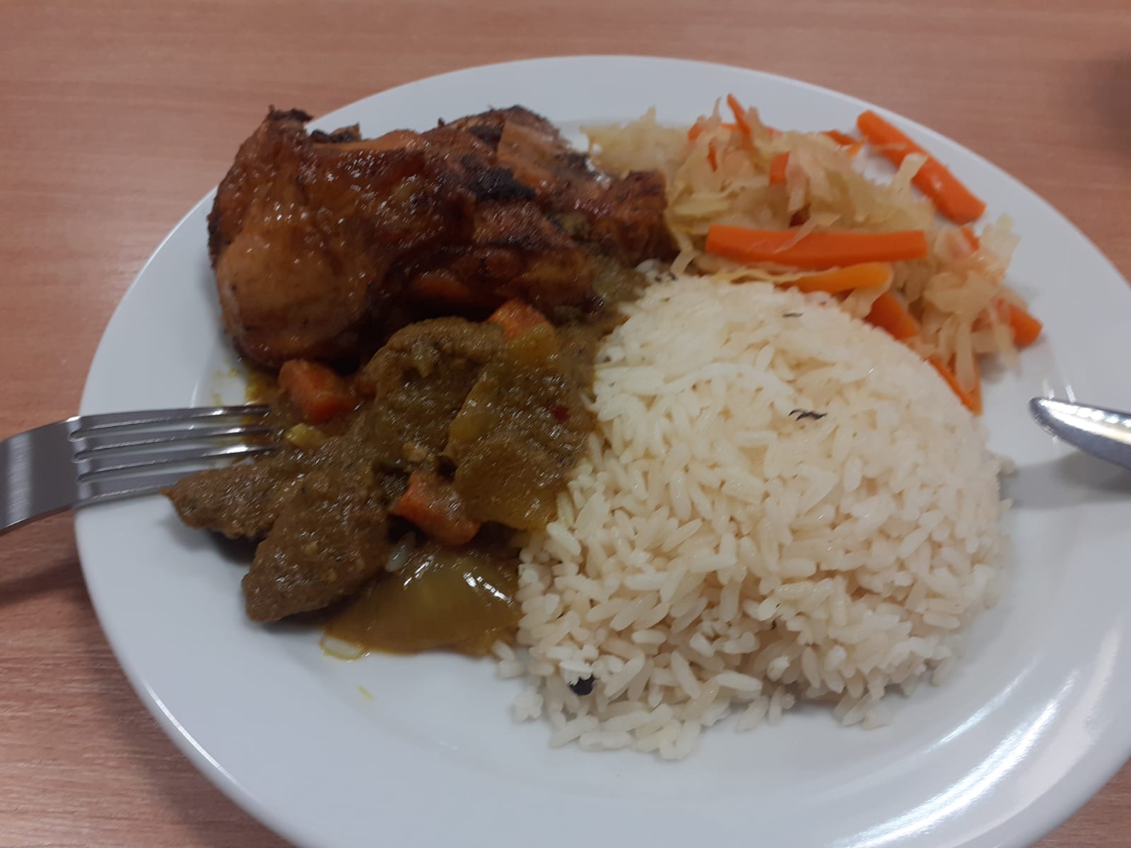 Plated meal with rice, curry, chicken, and coleslaw